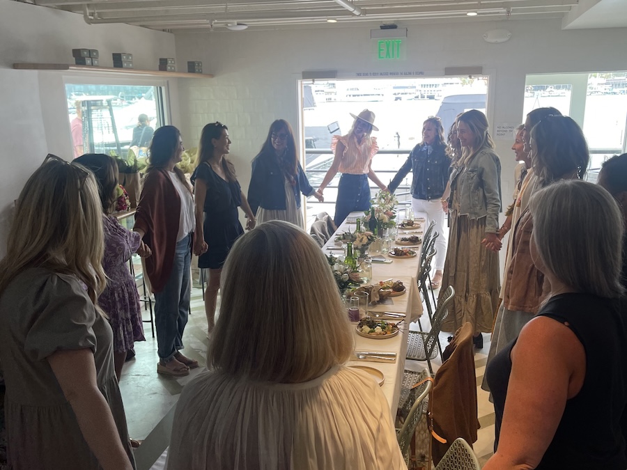 A group holds hands around a table set for a private event.