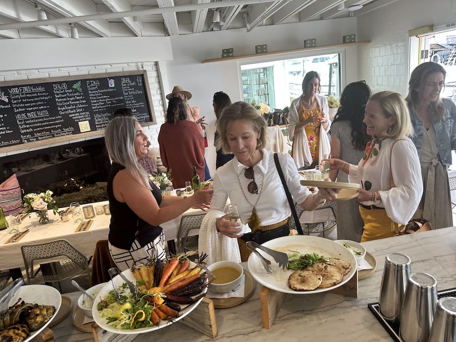 A group of guests explores the buffet spread of wood fired vegetables and pasta.